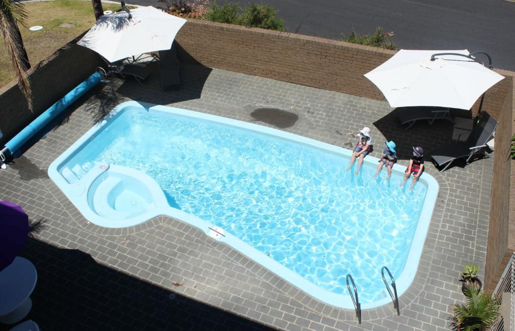 una vista aérea de una piscina con gente de pie en ella en Narooma Palms Holiday Apartments en Narooma