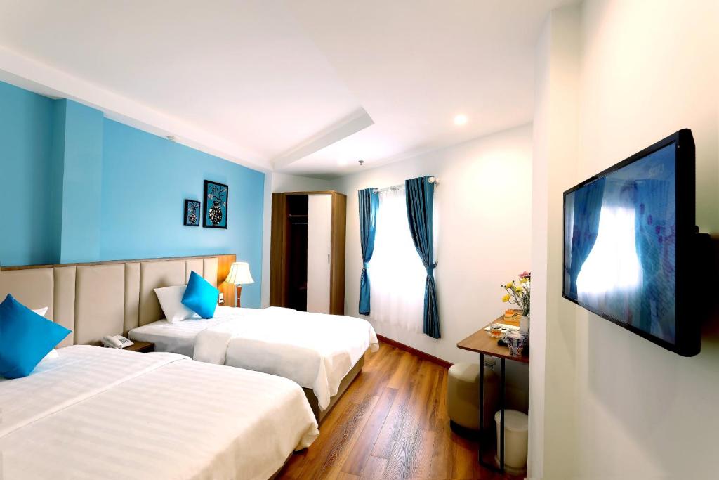 a hotel room with two beds and a flat screen tv at Sogo Hotel Saigon in Ho Chi Minh City