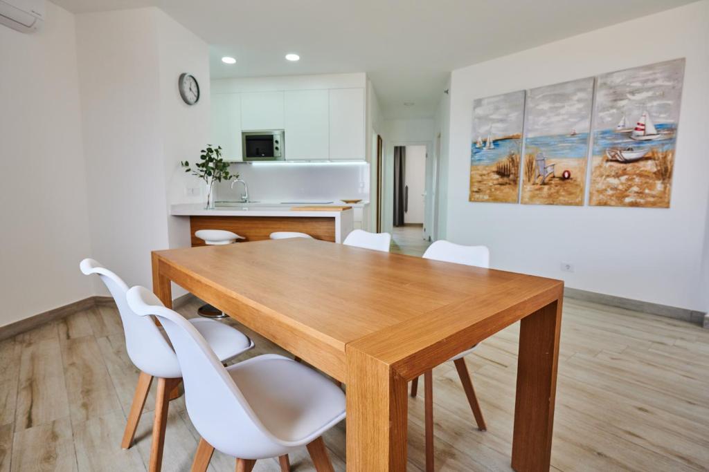 a dining room with a wooden table and white chairs at ABLANCAS - La Restinga in La Restinga