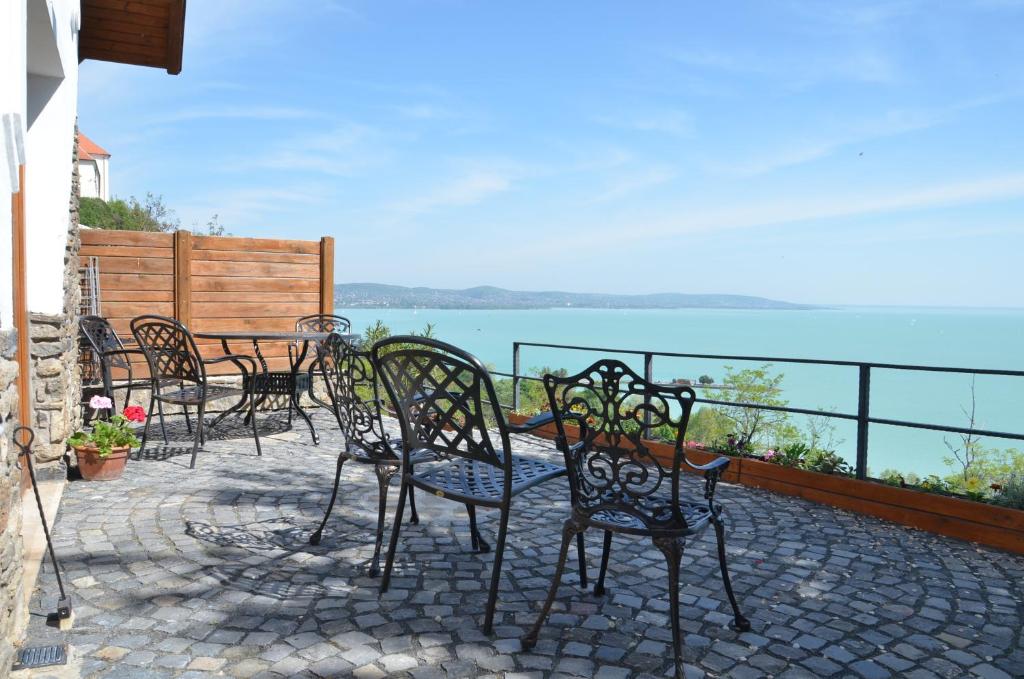 - un ensemble de chaises et de tables sur une terrasse donnant sur l'eau dans l'établissement Csátó Vendégház, à Tihany