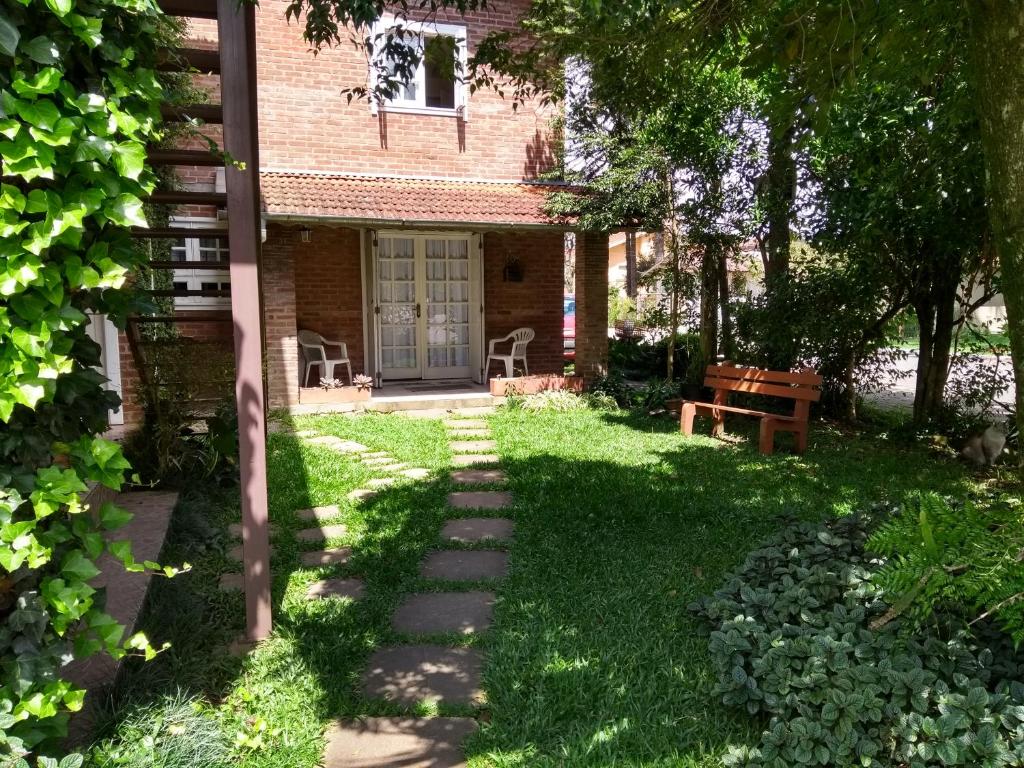 a garden with a house and a bench in the yard at Apartamento no Centro de Gramado in Gramado