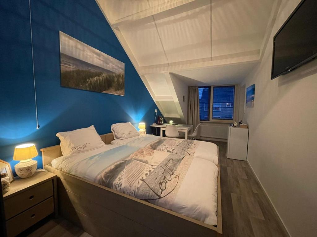 1 dormitorio con 1 cama grande y pared azul en Lise's Place, en Vrouwenpolder