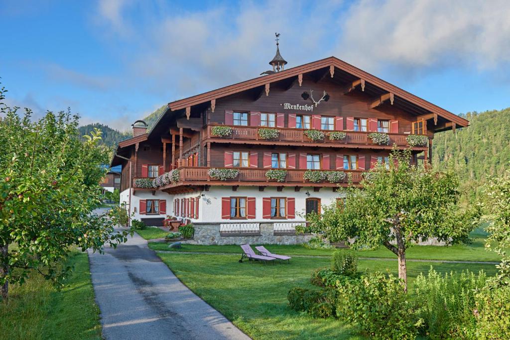 un gran edificio de madera con porche y patio de césped en Menkenhof en Reit im Winkl