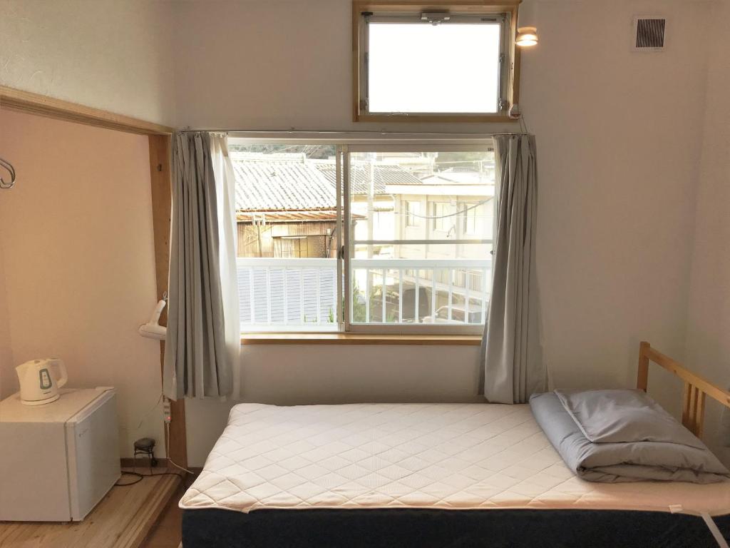 a small bedroom with a bed and a window at Tsushima White House in Tsushima