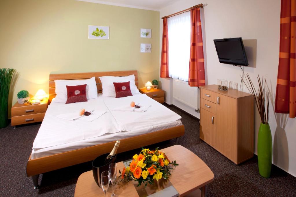 a hotel room with a bed and a tv at Penzion Oregano Třeboň in Třeboň