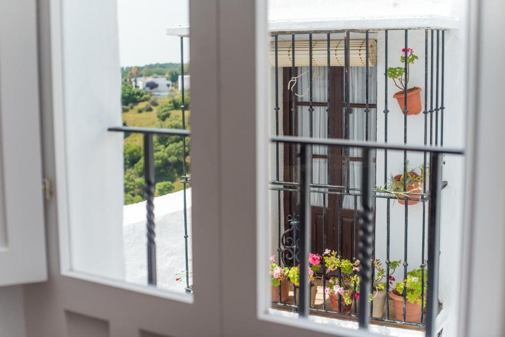 okno z widokiem na balkon z doniczkami w obiekcie Apartamento Trafalgar By La Juderia De Vejer - Inside a typical Andalusian Casa Patio w mieście Vejer de la Frontera