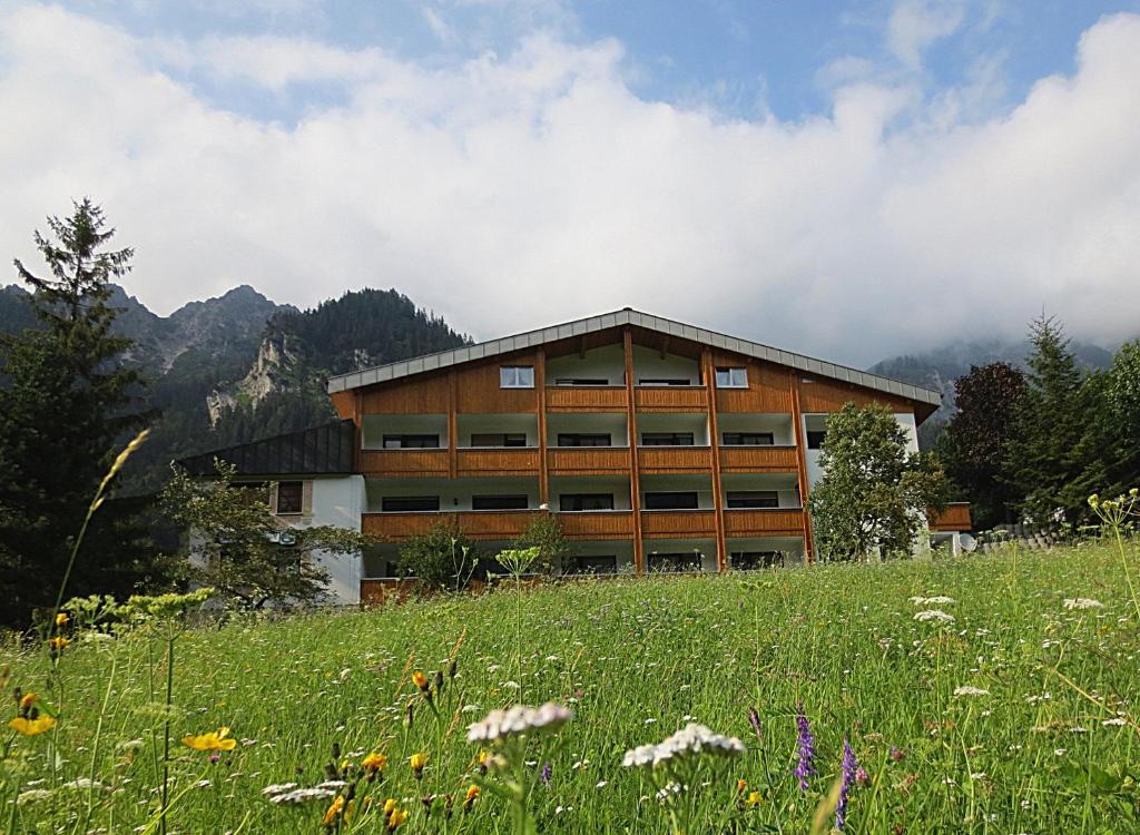a building on a hill with a field of flowers at Hotel Sonnblick in Wald am Arlberg