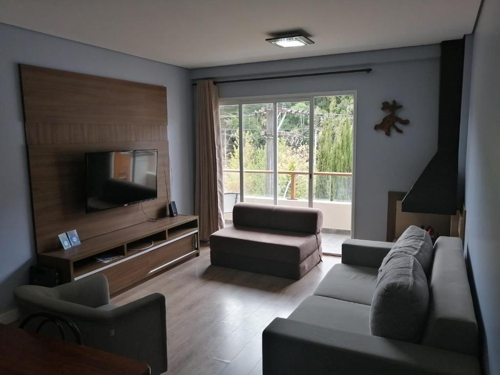 ein Wohnzimmer mit einem Sofa und einem TV in der Unterkunft CAPIVARI conforto in Campos do Jordão