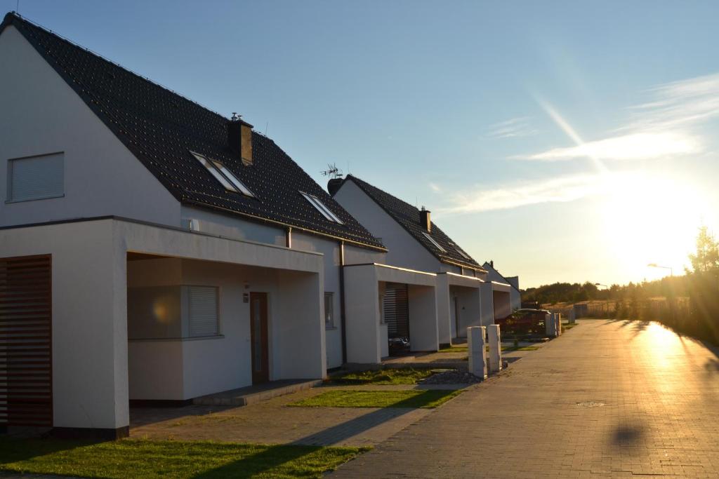 a row of houses with the sun setting in the background at Familienferienhaus Lilja - polnische Ostsee in Trzęsacz