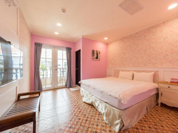 a bedroom with a large bed in a room with pink walls at Pretty Nanwan B&B in Nanwan