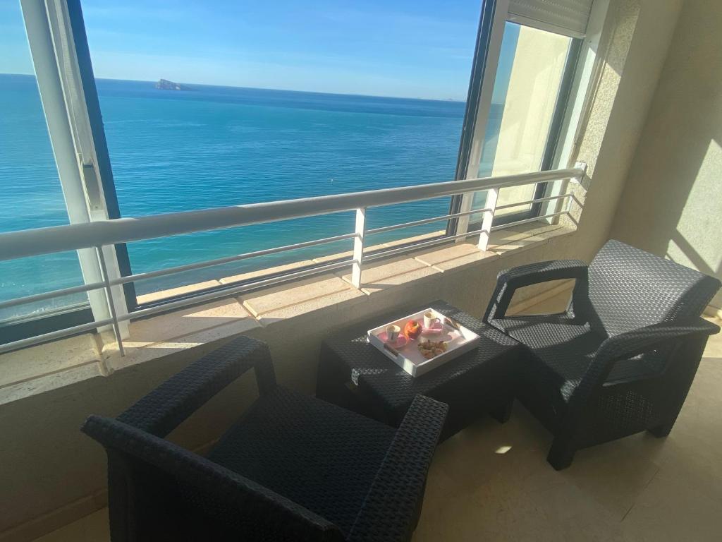 um quarto com uma mesa e cadeiras e vista para o oceano em Apartments Torre Levante 1H em Benidorm