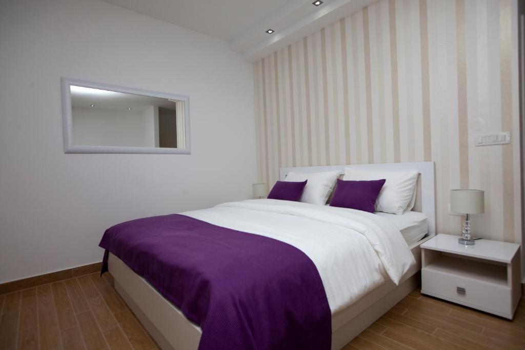 a white bedroom with a large bed with purple sheets at Rooms Ino in Kaštela