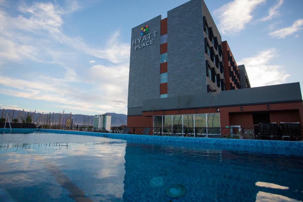 a hotel with a swimming pool in front of a building at Hyatt Place Saltillo in Saltillo