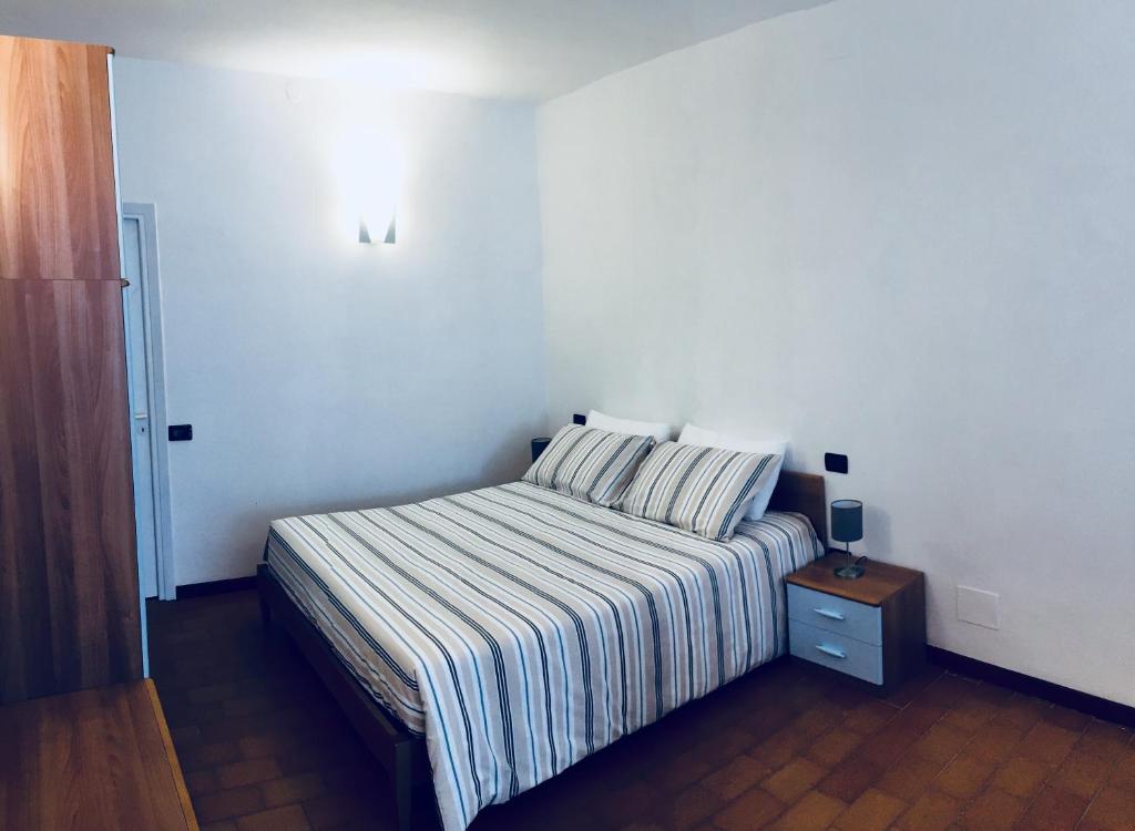 a bedroom with a bed with a striped blanket and a night stand at Sara Apartment, Comfort and lateral sea view in Riomaggiore