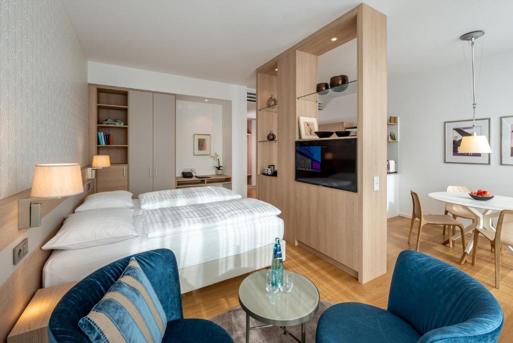 - une chambre avec un lit, une table et des chaises dans l'établissement Boutique Appartements im Berliner Tor, à Fribourg-en-Brisgau