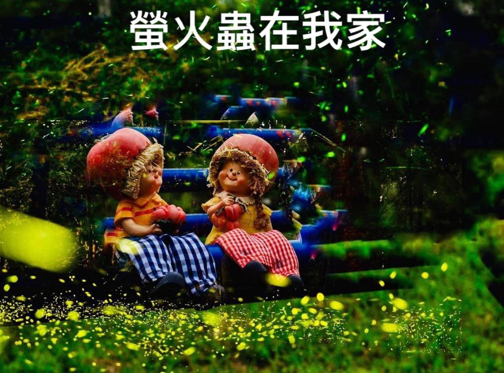 南庄的住宿－蓬萊生態農場仙山民宿，两个娃娃坐在带遮阳伞的长凳上