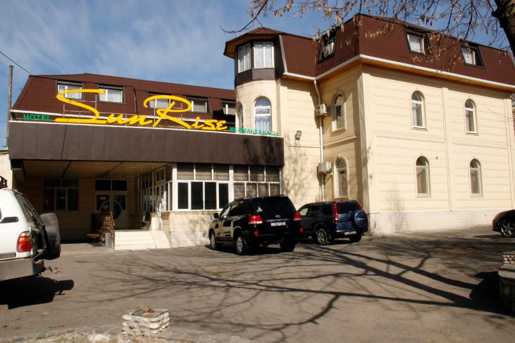 a building with two cars parked in front of it at Sunrise Guest House in Osh