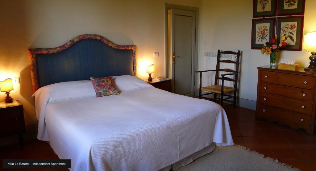 a bedroom with a large white bed with a blue headboard at Suite La Pieve Villa Le Barone Panzano in Chianti in Panzano