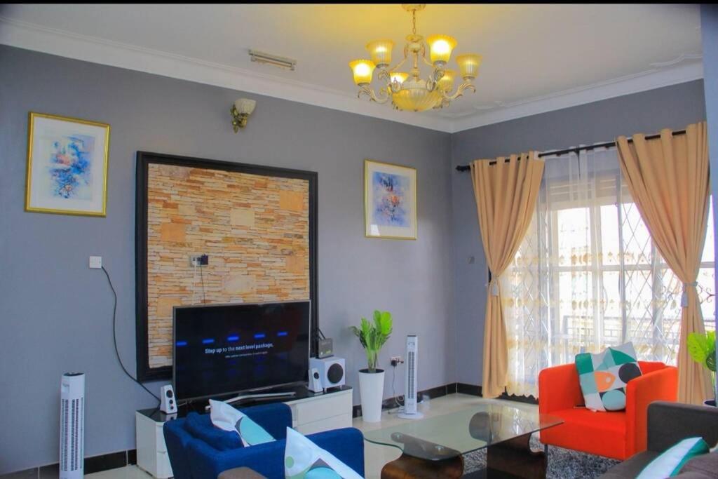 a living room with a flat screen tv and blue chairs at PNG Guest house Kitende in Kampala