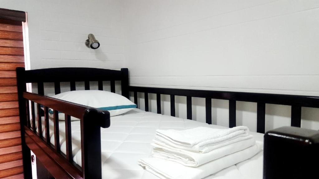- un lit bébé noir avec des draps blancs et des serviettes dans l'établissement Hostel Bravo, à Ferghana