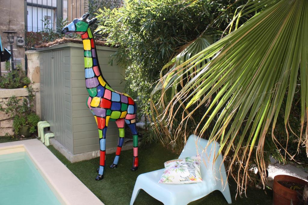 a colorful giraffe statue sitting next to a chair at H2o Chambres d'Hôtes in Peyriac-de-Mer