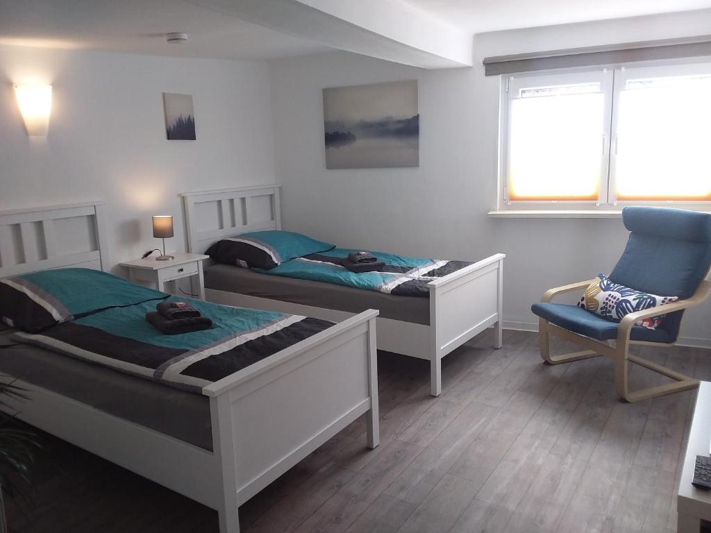 1 dormitorio con 2 camas, silla y ventana en Ferienwohnung Jansen "Zwei" en Bad Schwalbach