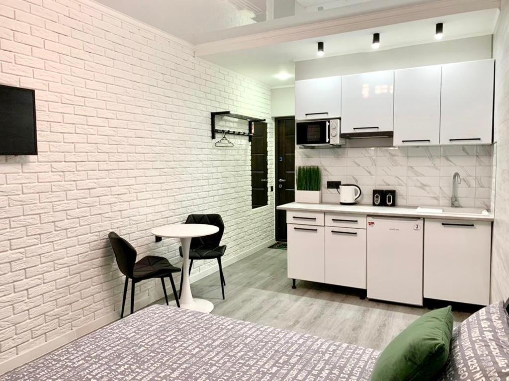 eine Küche mit weißen Schränken sowie einem Tisch und Stühlen in der Unterkunft Green room в ЖК Рич Таун Ирпень in Irpin