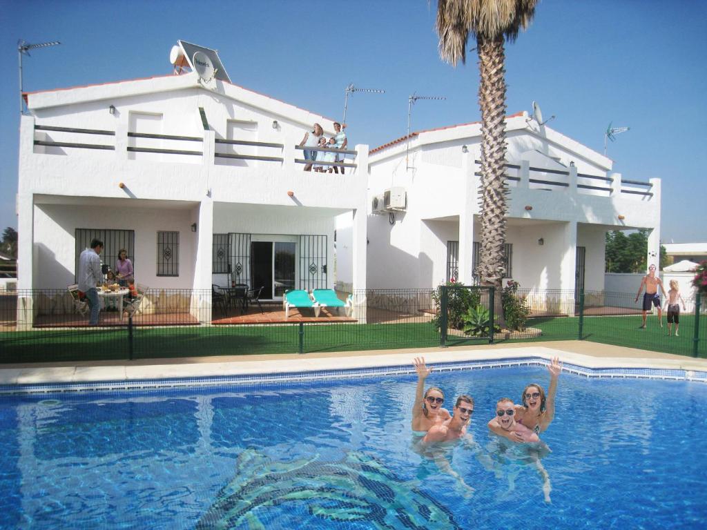 three women in a swimming pool in front of a house at Apartamentos Los Olivos in Conil de la Frontera
