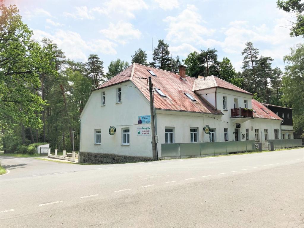 a white building with a red roof on the side of a road at Penzion Zelený Háj in Merklín