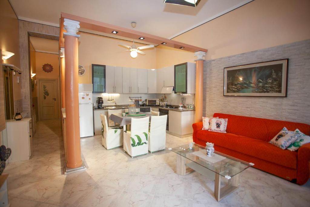 salon z czerwoną kanapą i kuchnią w obiekcie Casa RosaMaria w mieście Giardini Naxos