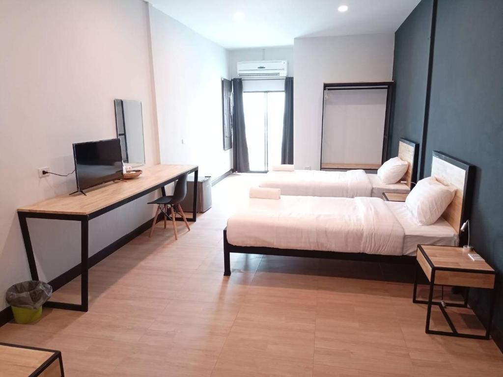 um quarto com 2 camas e uma secretária. em Sinai Hotel em Rayong