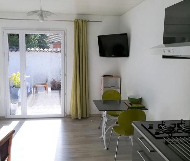eine Küche mit einem Tisch und Stühlen sowie eine Tür zu einer Terrasse in der Unterkunft Appartement au calme in Saint-Maurice-de-Gourdans