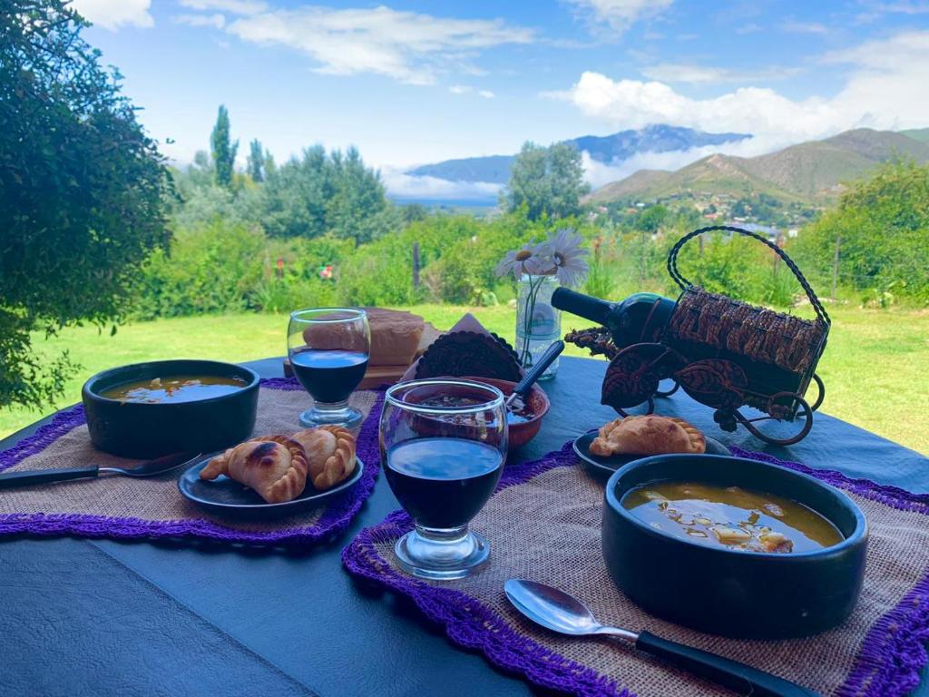stół z miskami jedzenia i kieliszkami wina w obiekcie HOSTAL ISABELLA w mieście Tafí del Valle