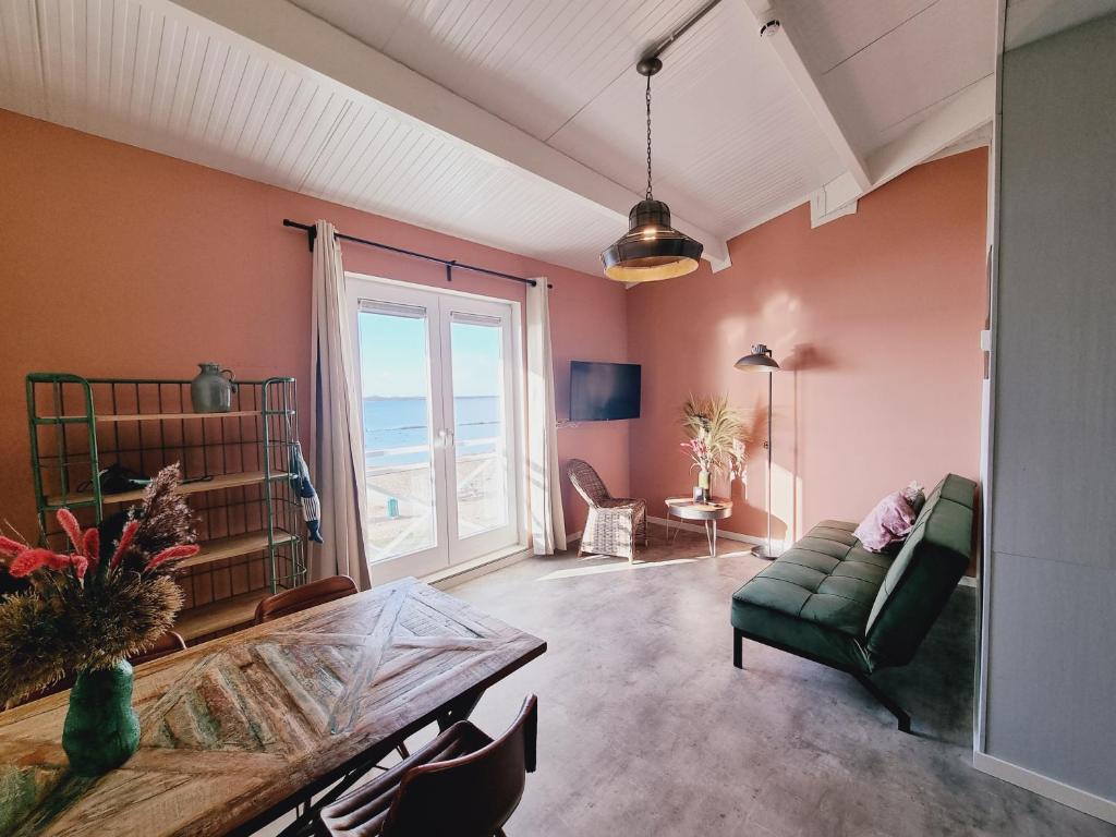 - un salon avec un canapé vert et une table dans l'établissement Beach Hotel Oostvoorne, à Oostvoorne