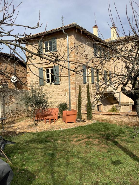 une grande maison en pierre avec un banc devant elle dans l'établissement Pivoines, à Saint-Julien