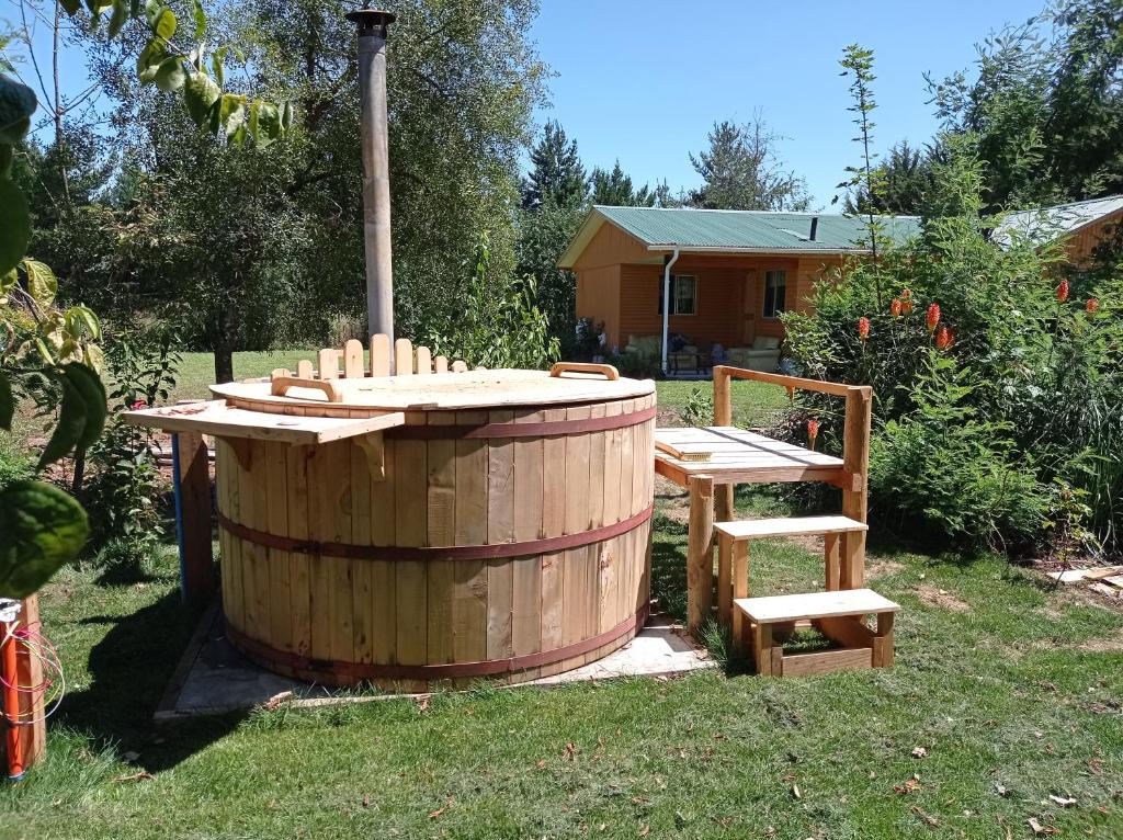 una bañera de hidromasaje de madera y un banco de madera en un patio en Vilcún, cabaña 100 mt2, a 38 k del Volcán Llaima, en Vilcún