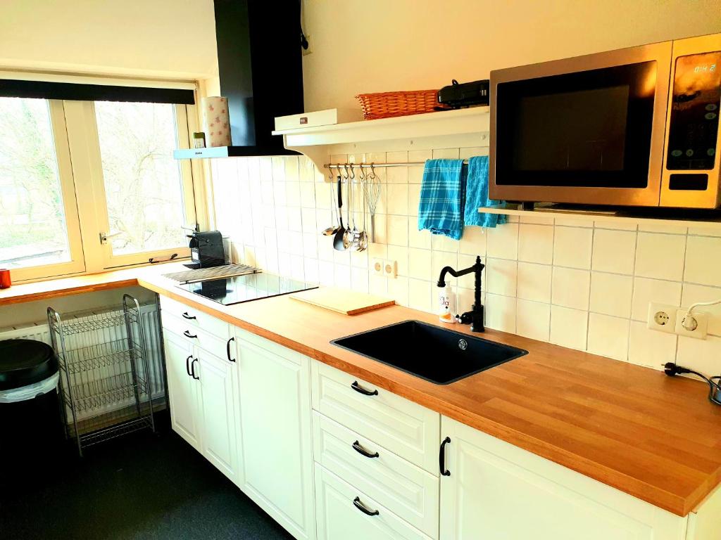 a kitchen with a sink and a microwave at Appartement Schoorl in Schoorl