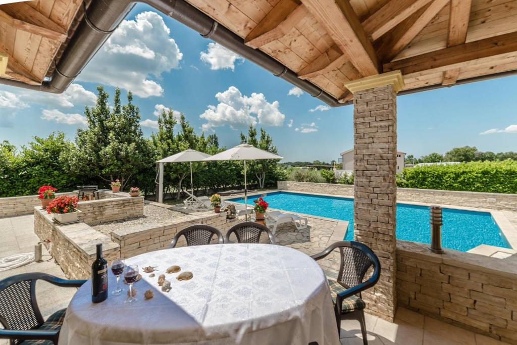 um pátio com uma mesa e cadeiras e uma piscina em Villa Ana with pool, large garden, near Zadar em Zadar
