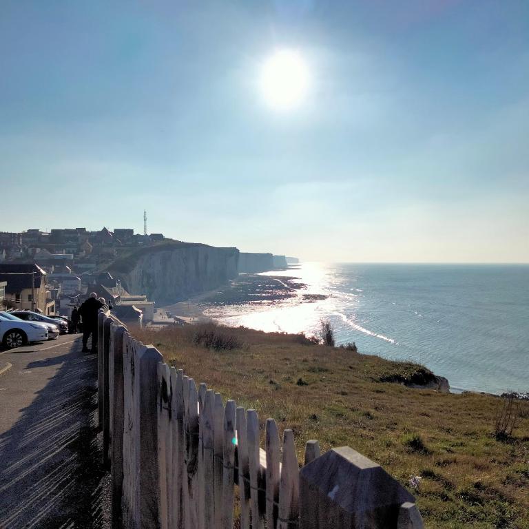 - une vue sur l'océan depuis une falaise avec une clôture dans l'établissement Petite Maison pleine de charme au Tréport....., au Tréport