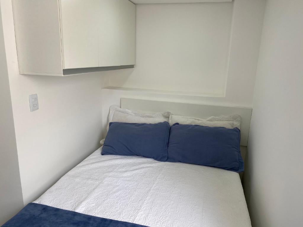 a small bedroom with a bed with two blue pillows at Pedra Branca in Campinas