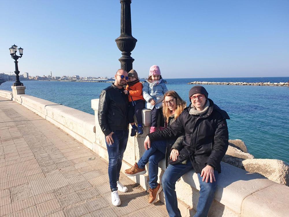 a group of people sitting on a bench next to the water at RosAmar in Bari