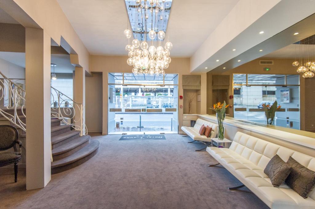 a living room with a couch and a chandelier at Hôtel Ligure in Cannes