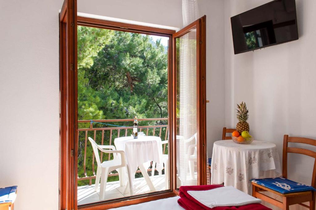 um quarto com uma varanda com uma mesa e uma janela em Niko Apartments em Drvenik