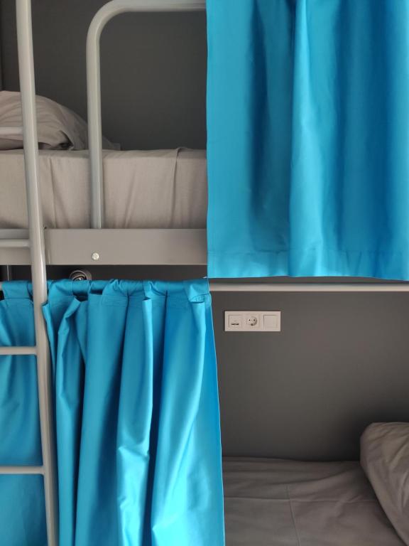 Ce lit superposé se trouve dans un dortoir doté de rideaux bleus. dans l'établissement Хостел с террасой в центре, à Kharkov