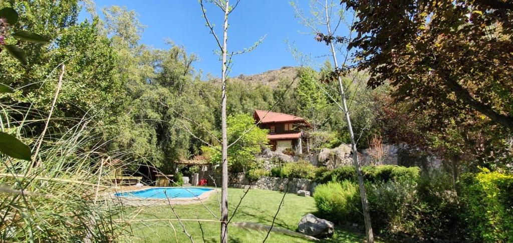 un jardín con una casa y una piscina en Casa de Montaña inmersa en Bosque Nativo en San José de Maipo