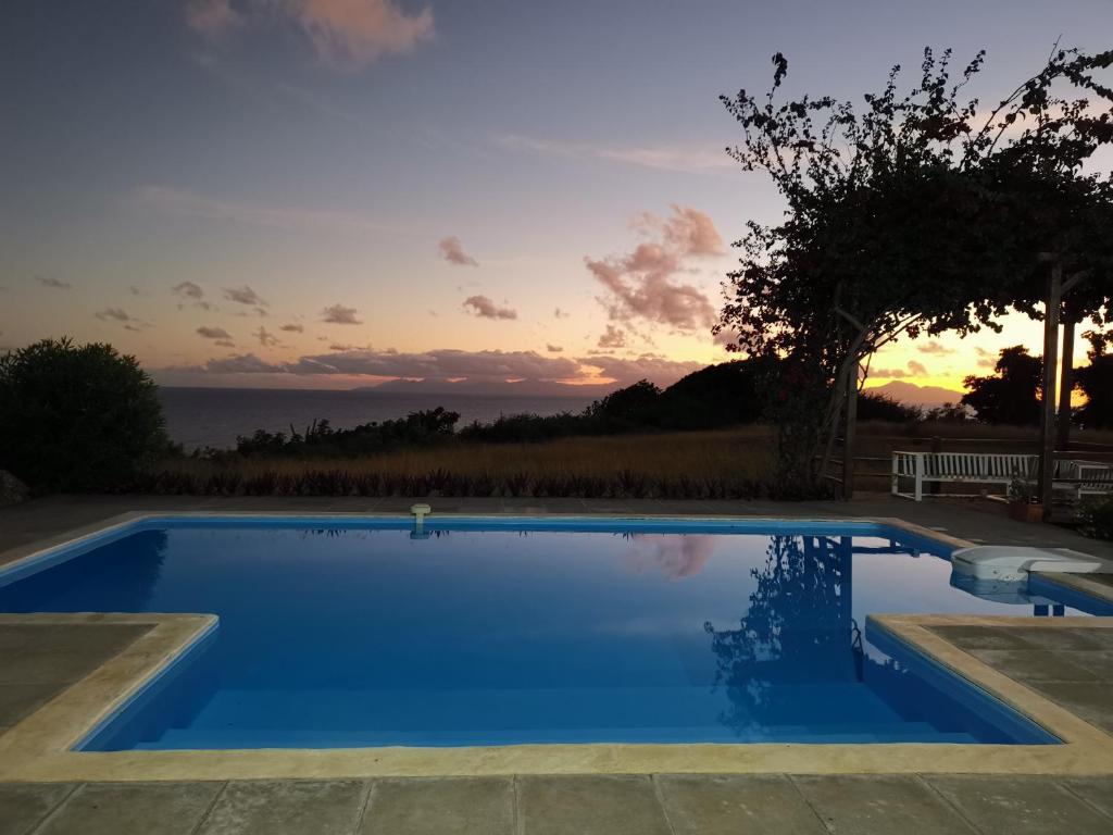 a blue swimming pool with a sunset in the background at Villa Maria'Landa in Capesterre