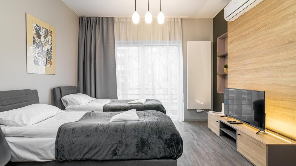 a hotel room with two beds and a flat screen tv at Comfy Apartments - Park Technologiczny in Gdynia