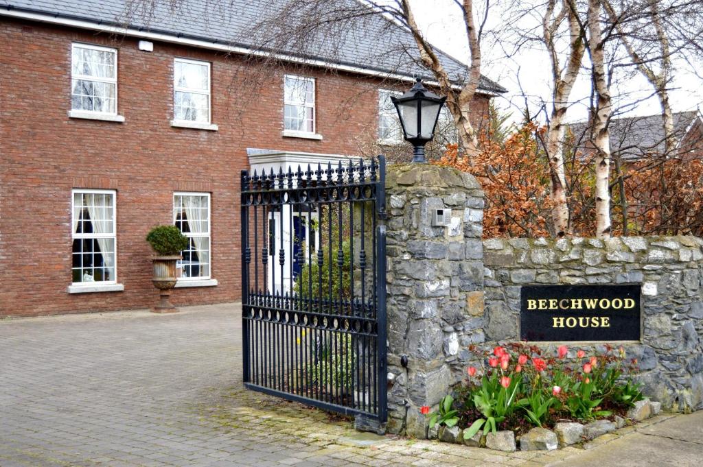 ein schwarzes Tor vor einem Backsteinhaus in der Unterkunft Beechwood Country House in Malahide