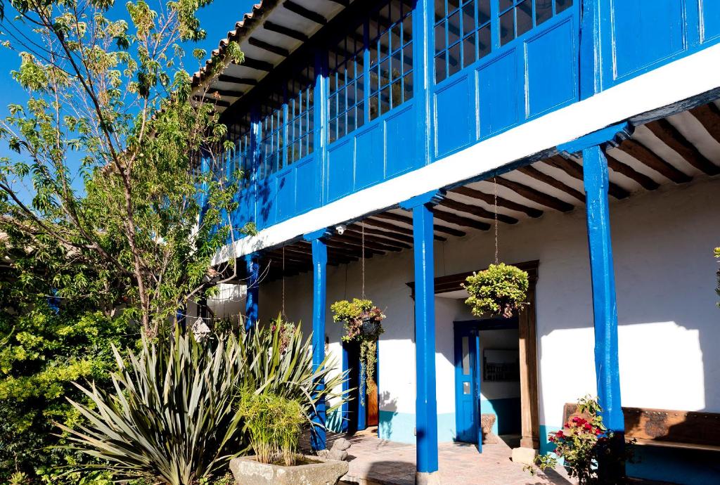 Cucunubá的住宿－Casa La Bisbal，一座蓝色的建筑,前面有植物