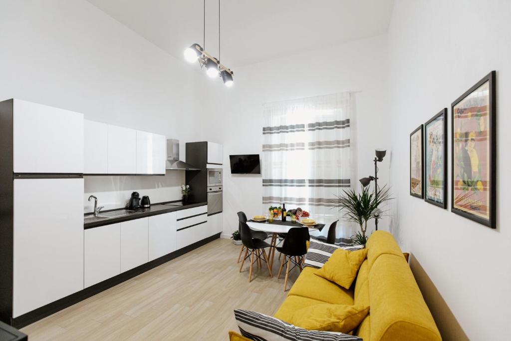 ein Wohnzimmer mit einem gelben Sofa und einer Küche in der Unterkunft Les Amis in Syrakus